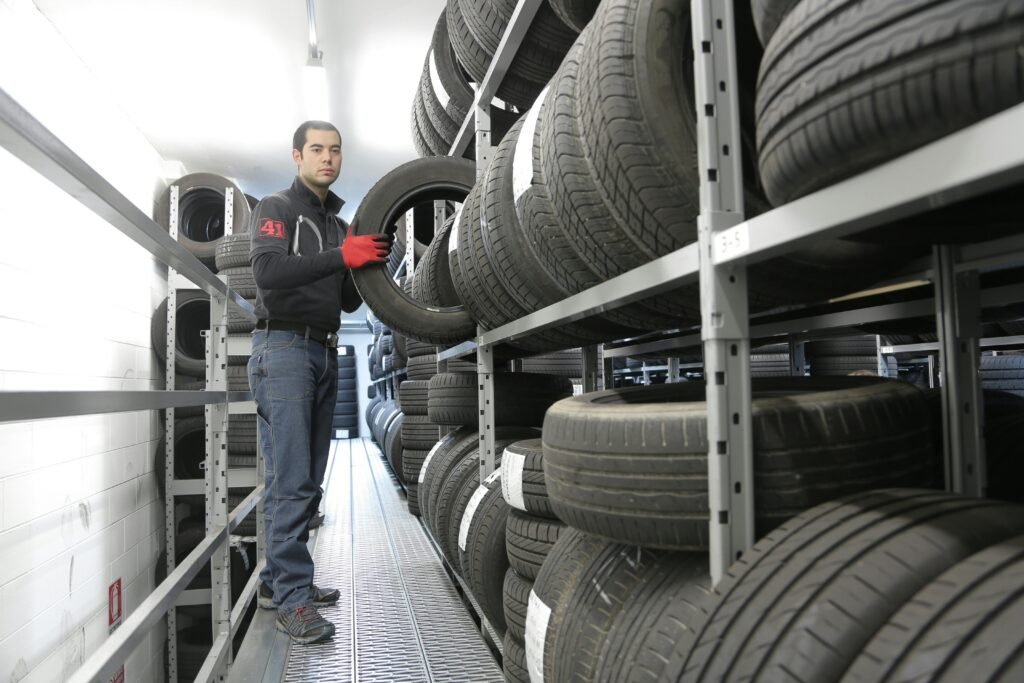 pexels-photo-3807167-3807167 Mechanic places a tire on a rack in an indoor warehouse storage facility.